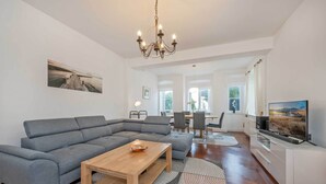 A modern living room with a grey sectional sofa, a wooden coffee table, and a flat-screen TV. - Villa Meereswoge 02 - directly on the pier (Bansin (Seebad))