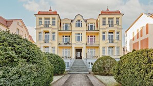 A multi-story building with a central entrance, symmetrical balconies, and a formal architectural style. - Villa Meereswoge 02 - directly on the pier (Bansin (Seebad))