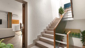 A modern interior with a staircase, a sofa, and a painting.