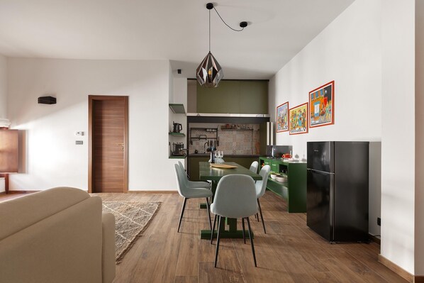 A modern kitchen with a dining area, wooden flooring, and a green accent wall. - 3251 Dellatita Suite by Barbarhouse (Lecce)
