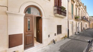 A narrow street with historic buildings featuring arched doorways and balconies.