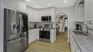 Una cocina moderna con armarios blancos, electrodomésticos de acero inoxidable y encimera de granito.
