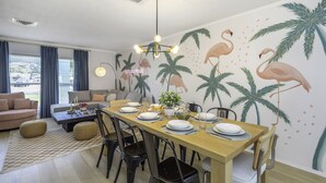 Un comedor con una mesa de madera dispuesta para cuatro personas, rodeada de sillas, un sofá y una mesa baja.