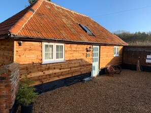 Ein Holzhaus mit Ziegeldach, einer Ziegelwand und einem Schotterweg.