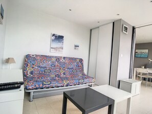 Ein modernes Wohnzimmer mit einem gemusterten Sofa, einem kleinen Tisch und Blick ins Freie.