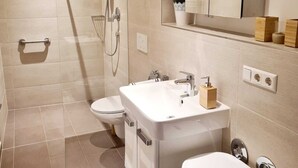 Un baño moderno con cabina de ducha, inodoro, lavamanos y bidé.