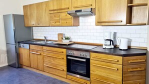 Una cocina moderna con armarios de madera, un refrigerador de acero inoxidable, horno empotrado y cafetera.