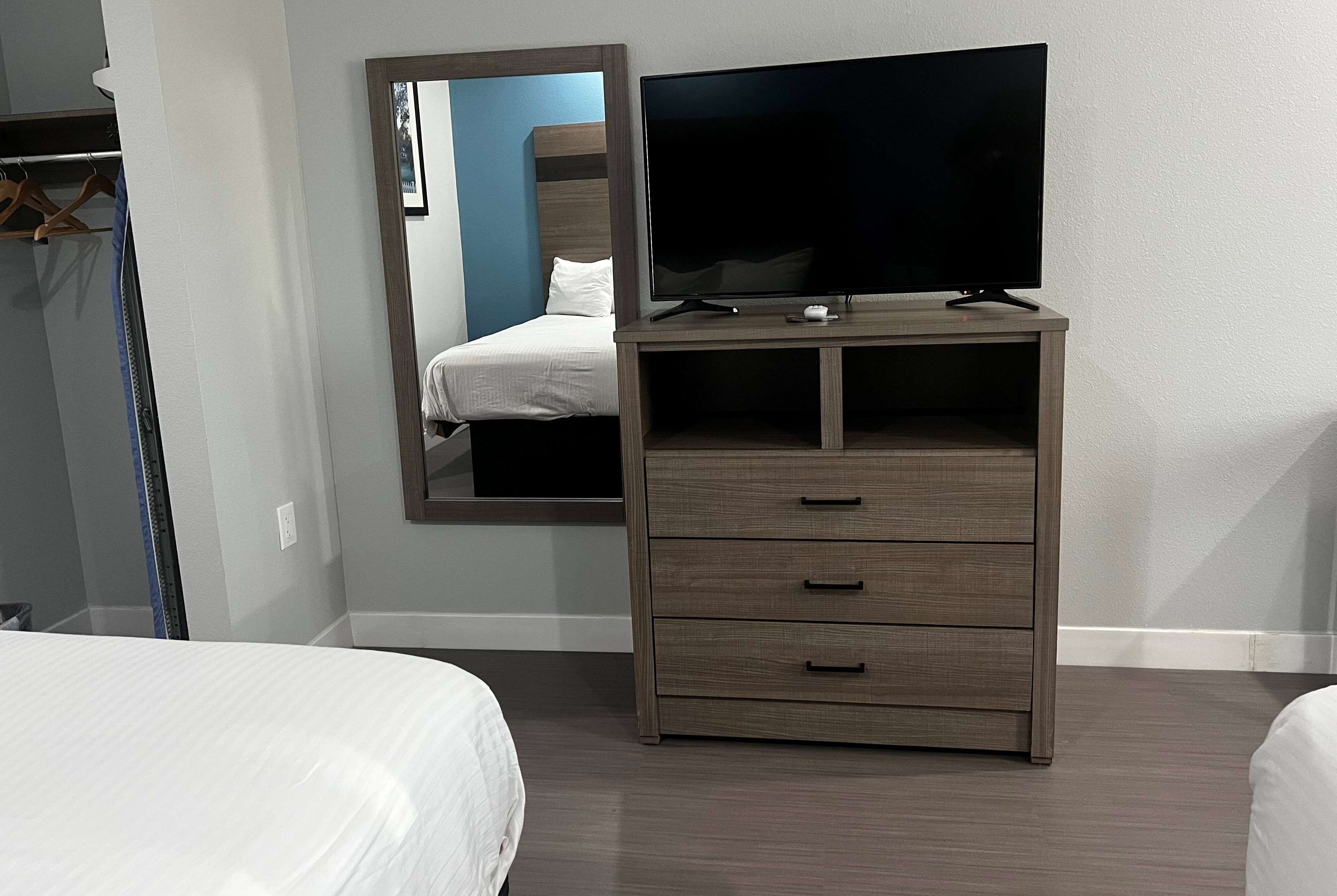 Una camera d'albergo con un letto, una televisione su un mobile in legno, uno specchio e un armadio.