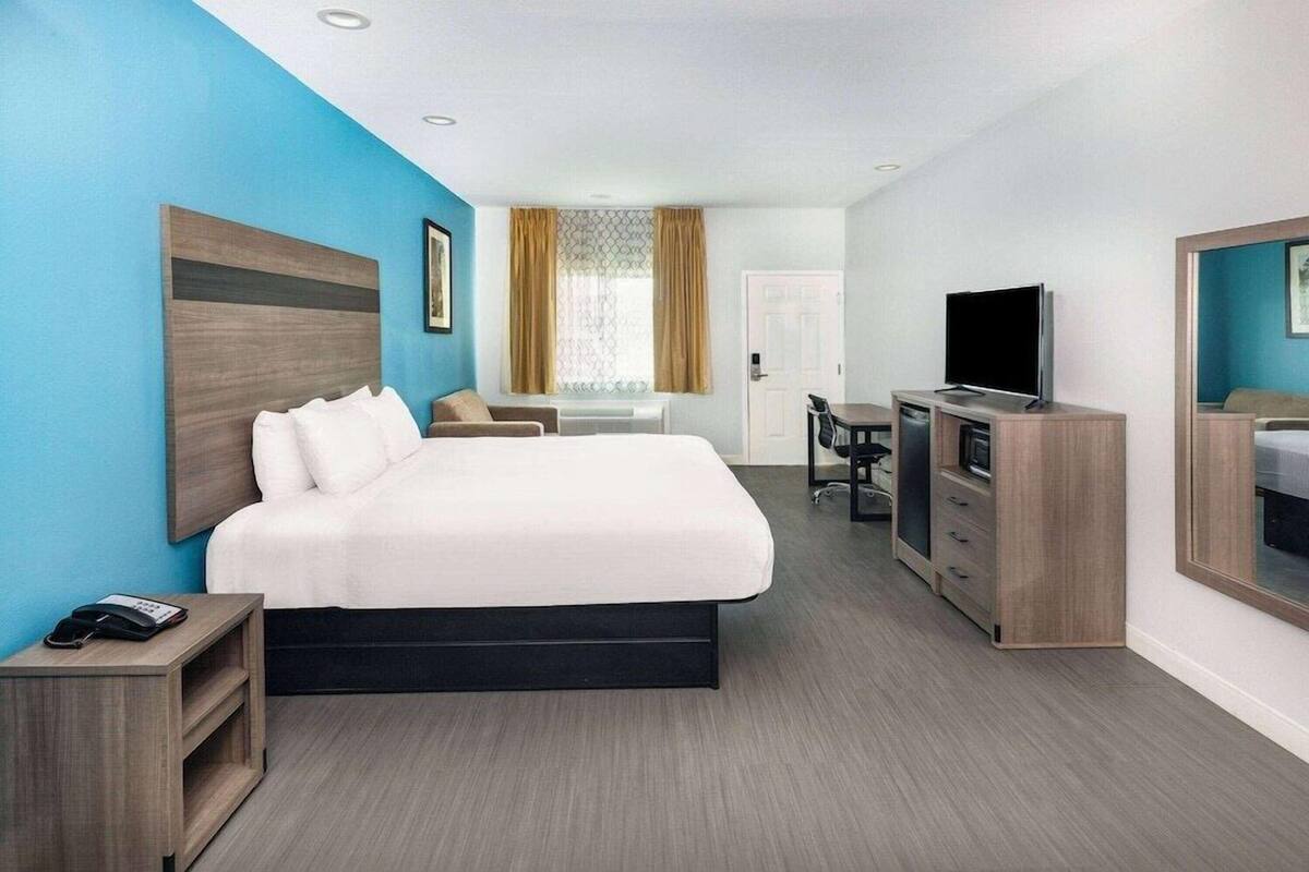 Ein Hotelzimmer mit Bett, Schreibtisch, Fernseher und Kleiderschrank.