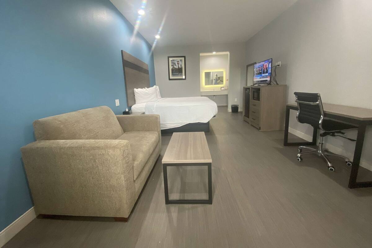 Ein Hotelzimmer mit Bett, einer Couch, einem Schreibtisch und einem Fernseher.