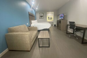 A hotel room with a bed, a sofa, a desk, and a TV.