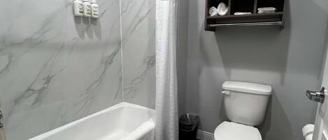 A bathroom with a bathtub, toilet, and a shelf with towels.