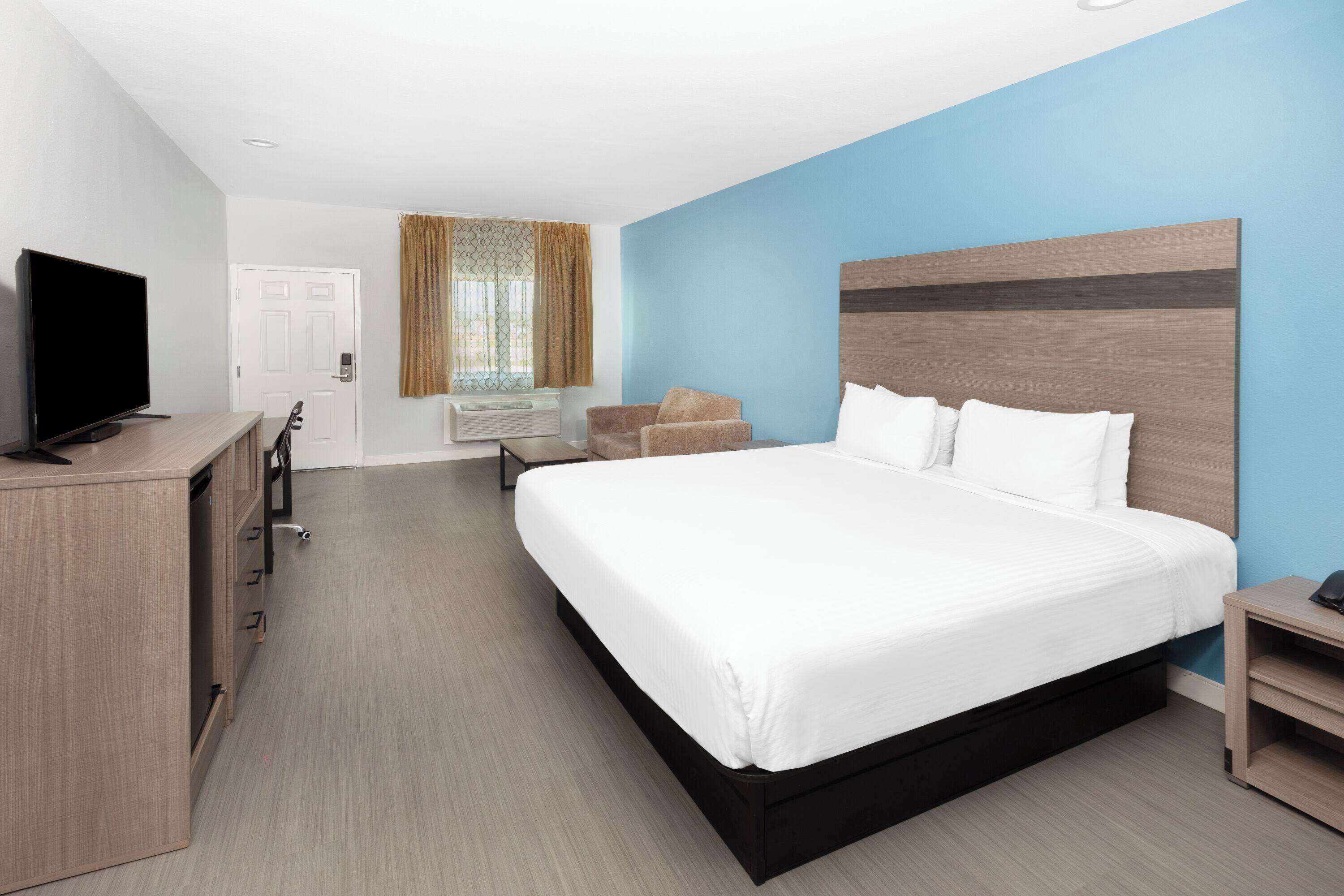 Ein Hotelzimmer mit einem großen Bett, einem Fernseher, einem Schreibtisch und einem Sessel.