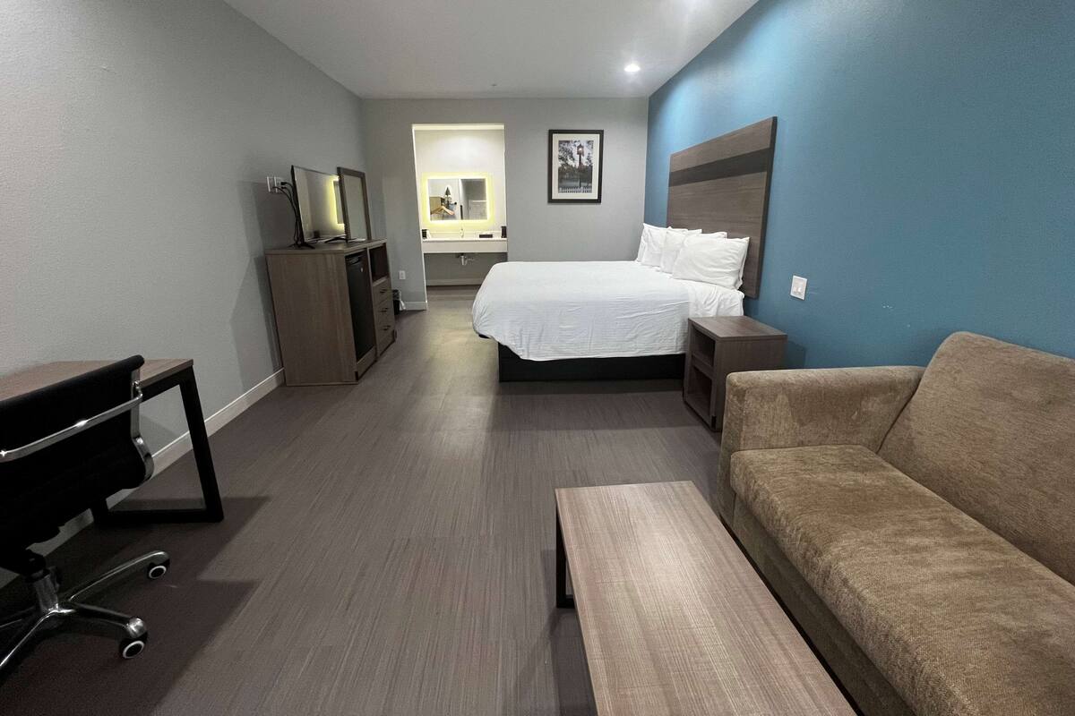 Ein Hotelzimmer mit Bett, Sofa, Schreibtisch und Fernseher.