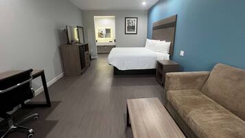 Una habitación de hotel con cama, sofá, escritorio y televisor.