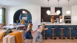 Eine moderne Küche mit Kochinsel, Barhocker und Pendelleuchten.