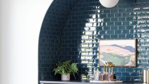 Eine moderne Küche mit blau gefliestem Rückspritzschutz, Holzschränken und einem Essbereich mit rundem Tisch und Stühlen.
