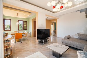 Una sala de estar con televisor, sofá y comedor.