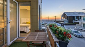 A balcony with a bed, a table, and potted plants. - Apartment 'Costa Nova Ocean View' with Sea View, Wi-Fi and Air Conditioning (Gafanha da Encarnação)