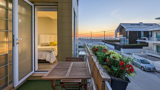 Un balcone con un letto, un tavolo e piante in vaso.
