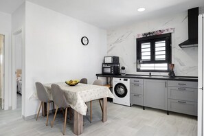 A compact kitchen with a washing machine, a microwave, and a dining area with a table and chairs.
