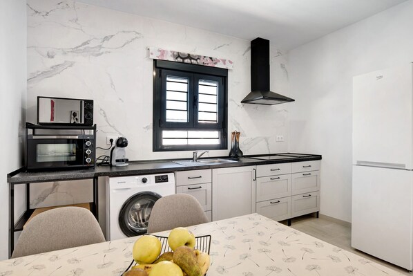 A compact kitchen with a microwave, washing machine, and a window.