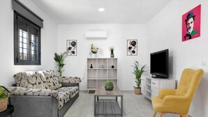 A living room with a sofa, a yellow armchair, a coffee table, a TV, and a bookshelf. - Holiday Home 'La Posada' with Pool, Garden, Terrace & Wi-Fi (Conil de la Frontera)