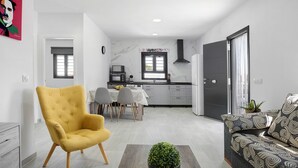 A modern kitchen with a dining area, a yellow armchair, and a sofa with a patterned design. - Holiday Home 'La Posada' with Pool, Garden, Terrace & Wi-Fi (Conil de la Frontera)