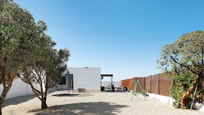 An outdoor area with a gravel ground, a swing set, and a building with a white exterior. - Holiday Home 'La Posada' with Pool, Garden, Terrace & Wi-Fi (Conil de la Frontera)