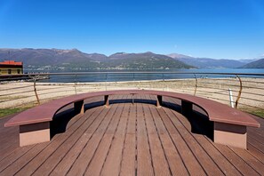 A wooden deck with benches overlooking a lake and mountains.