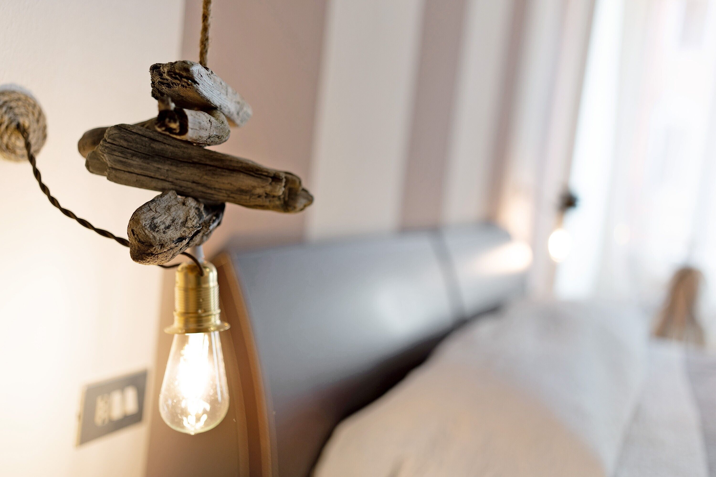 Een detailopname van een rustieke lamp met een gloeilamp, een houten element en touw.
