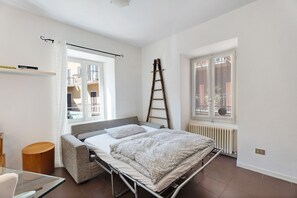 Une chambre à coucher avec un lit, une échelle, une fenêtre et un radiateur.