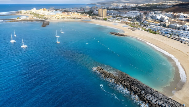 A coastal town with a sandy beach, clear blue waters, and several sailboats. - Vacation Home 'Bonito Apartamento Cristian Playa' with Balcony & Wi-Fi (Arona)