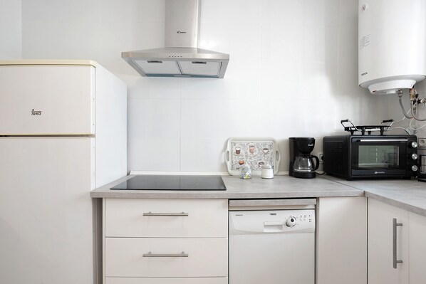 Une cuisine moderne équipée d’un lave-vaisselle intégré, d’une machine à café et d’un four à micro-ondes.