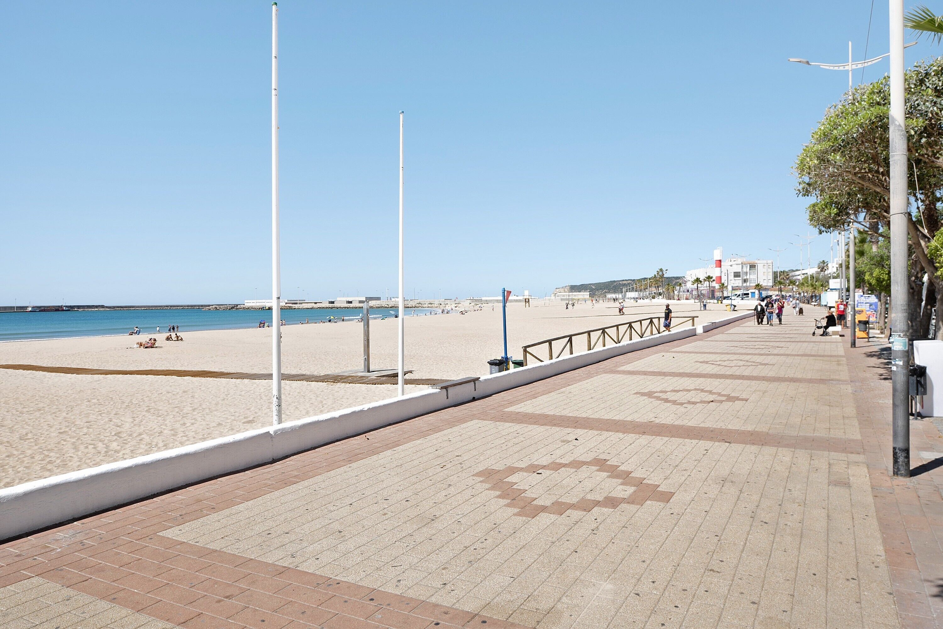 Un chemin pavé mène à une plage, et le ciel est dégagé.