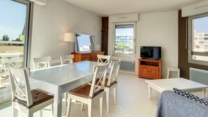 Una sala de estar moderna con una mesa de comedor, sillas, un televisor y un sofá.