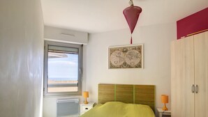 Un dormitorio con cama, ventana con vistas, mapa en la pared y armario.
