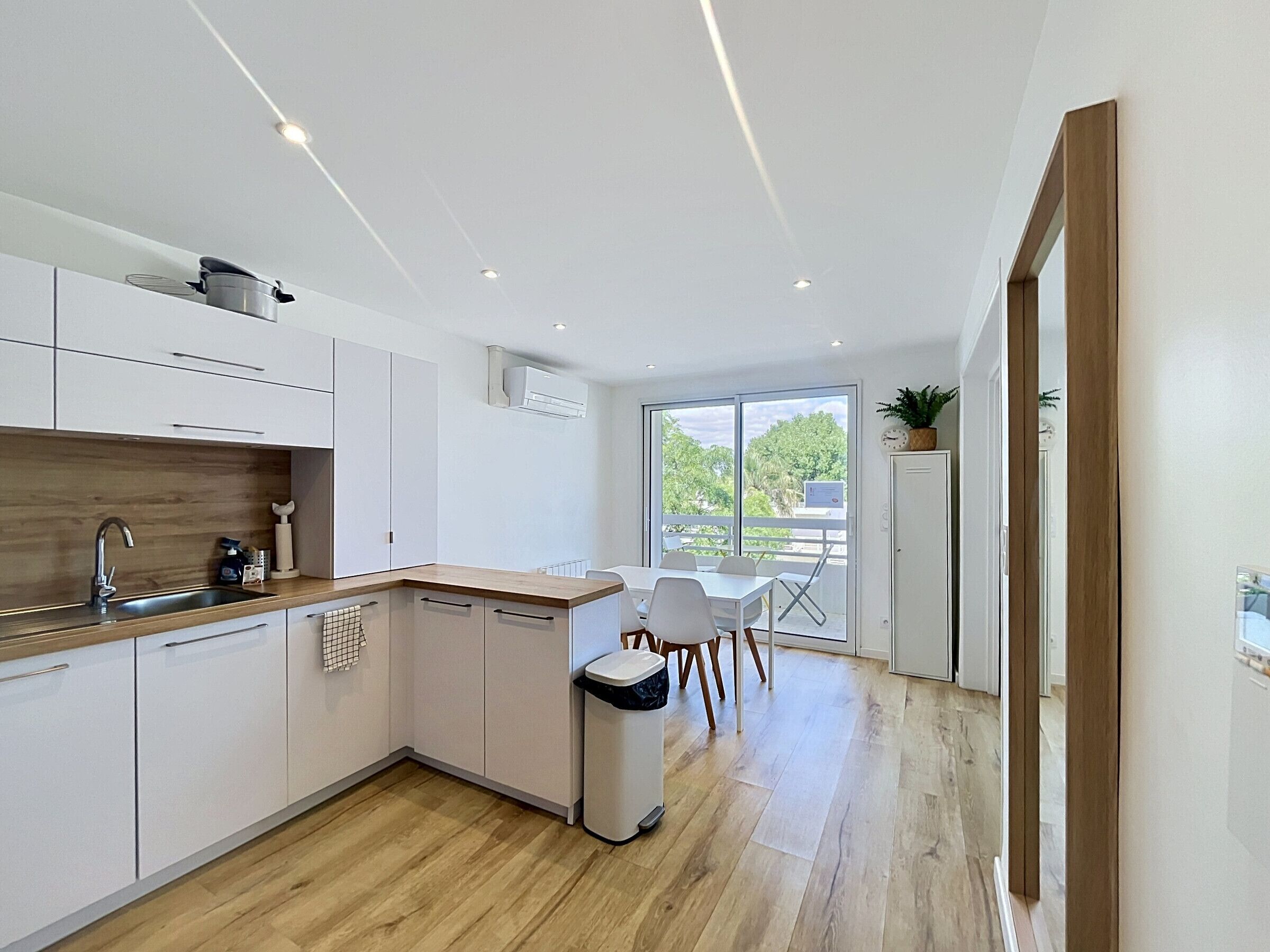 Eine moderne Küche mit weißen Schränken, einer Holz Arbeitsplatte und Blick auf Grünfläche.