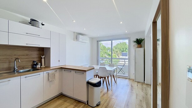 Eine moderne Küche mit weißen Schränken, einer Holz Arbeitsplatte und Blick auf Grünfläche.