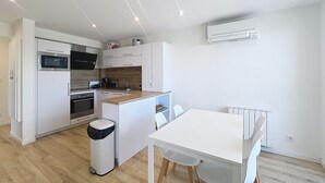 Eine moderne Küche mit weißen Schränken, einem Backofen, einer Mikrowelle und einer kleinen Kochinsel mit Spüle.