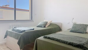 Ein Zimmer mit zwei Betten, einem Fenster, einer Klimaanlage und einer Heizung.
