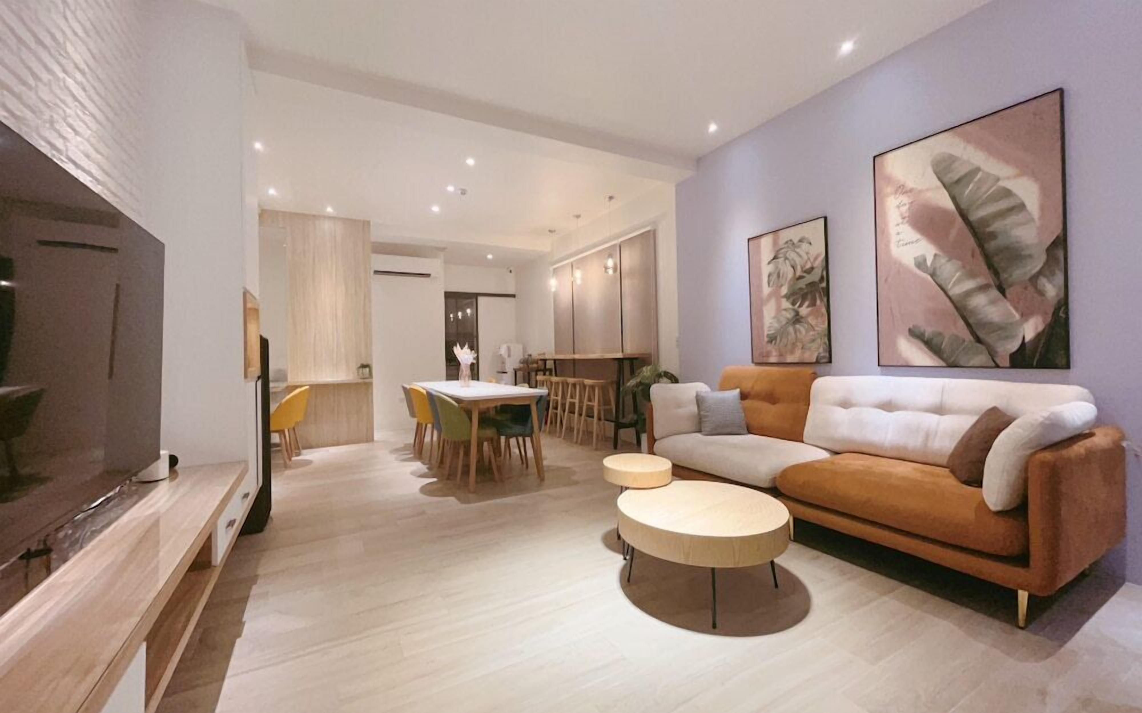A modern living room with a sofa, coffee table, and a dining area with chairs and a table.