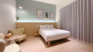 A modern hotel room with a bed, a sofa, a small table, and a wall-mounted light fixture. - House in field (Dongshan)