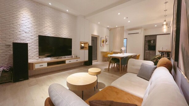 A modern living room with a flat-screen TV, a dining area, and a kitchen in the background. - House in field (Dongshan)