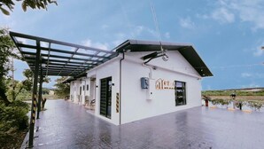 A modern building with a flat roof, large windows, and a covered outdoor area. - House in field (Dongshan)