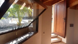 Una habitación con techo de madera, una ventana con vista a un jardín y una puerta de madera.