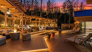An outdoor deck with a fire pit, lounge chairs, and a waterfall feature.