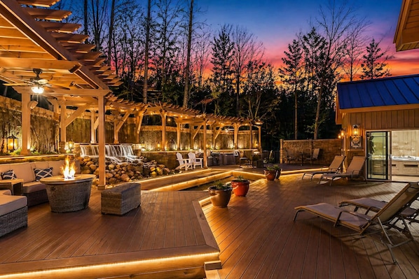 An outdoor deck with a fire pit, lounge chairs, and a waterfall feature.