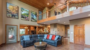 A spacious living room with a large sectional sofa, a wooden coffee table, and a view of the kitchen and dining area.
