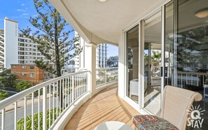 Enjoy the view from this balcony with a glass door leading to an outdoor space, a small table, and a comfortable chair.